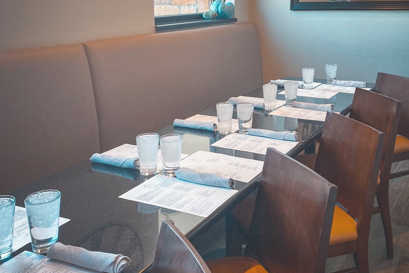 A booth table at Elements set for two, with the dining room wall clock on the wall behind it.
