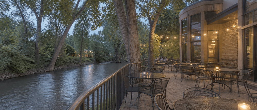 Concept image of the riverside patio at dusk, lit by string lights.