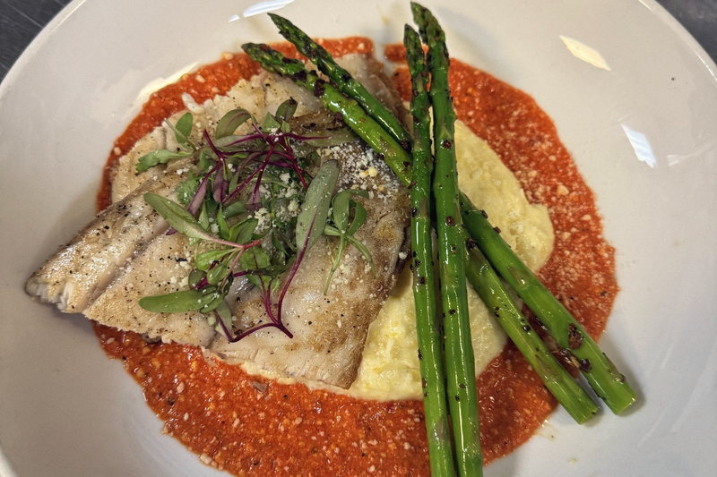 Seared fish on romesco sauce with grilled asparagus, photographed from directly above.