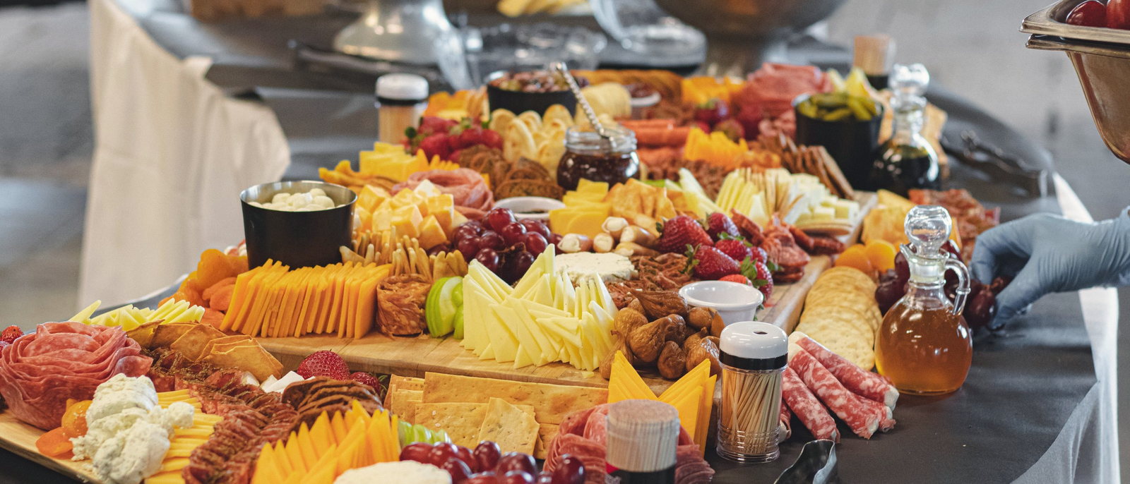 A full grazing table laid end to end with charcuterie, cheeses, fresh fruit and honey.