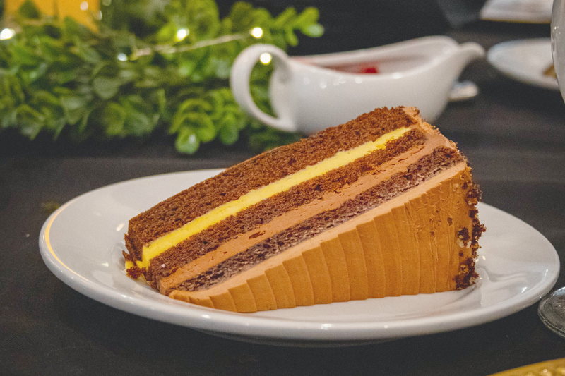A slice of chocolate layer cake plated with a sprig of mint.