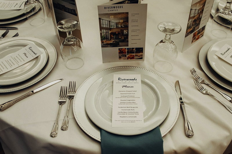 A place setting with a printed Riverwoods Campus menu card standing at the center of the plate.
