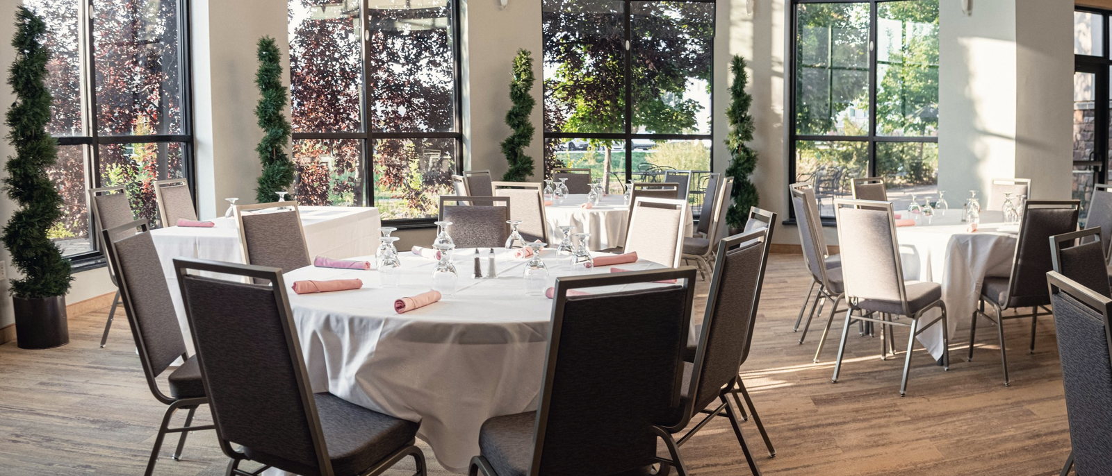 Round tables set beneath the tall windows of the glass rotunda at The Riverwoods, shot as a panorama.