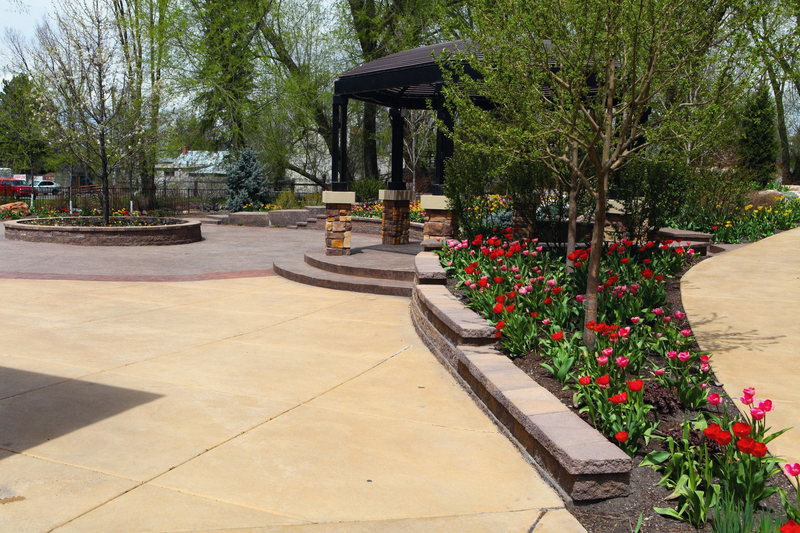 The Birch Courtyard: stamped paving, a dark metal gazebo and tulip beds in flower.
