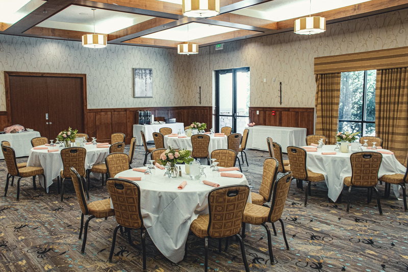 The Willow room set with round tables under a coffered ceiling with square pendant lights and gold drapery.