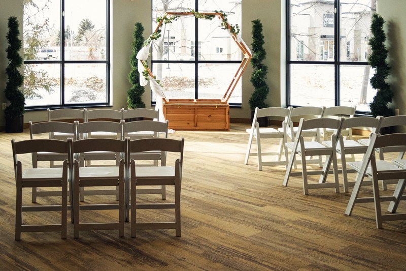 The Poplar set with white chairs for a small ceremony in front of a two-story window wall.
