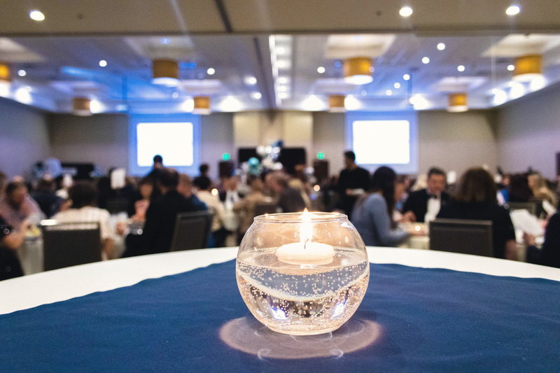 A floating candle burning in a glass globe on a navy table runner, with the rest of the table thrown out of focus.